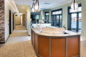 Reception area featuring a curved desk, hanging lights and a hallway to exam rooms and the restroom