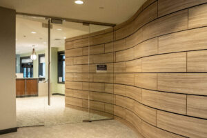 Hallway with a curved wood slat wall leading ups the the glass doors to Mercy Health Concierge Medicine