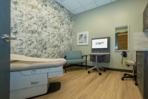 Patient exam room with an examination table, chair, cabinets and workstation