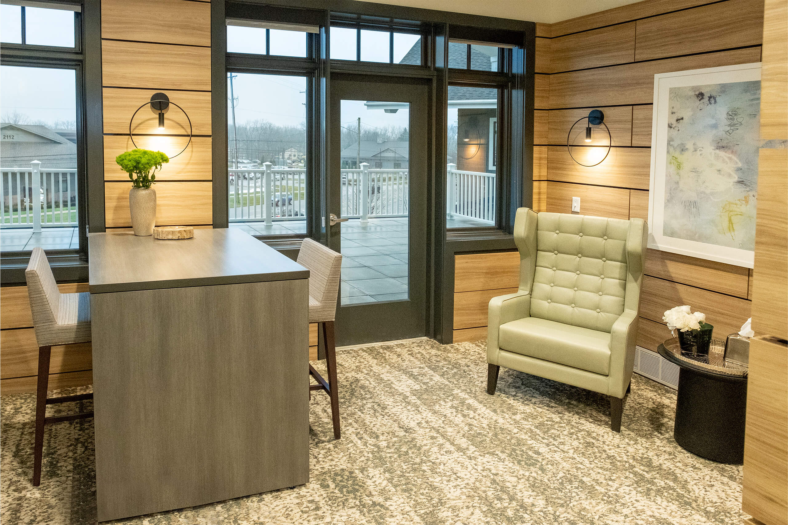 Meeting room with wood slat walls, a light green accent chair and a table with two chairs