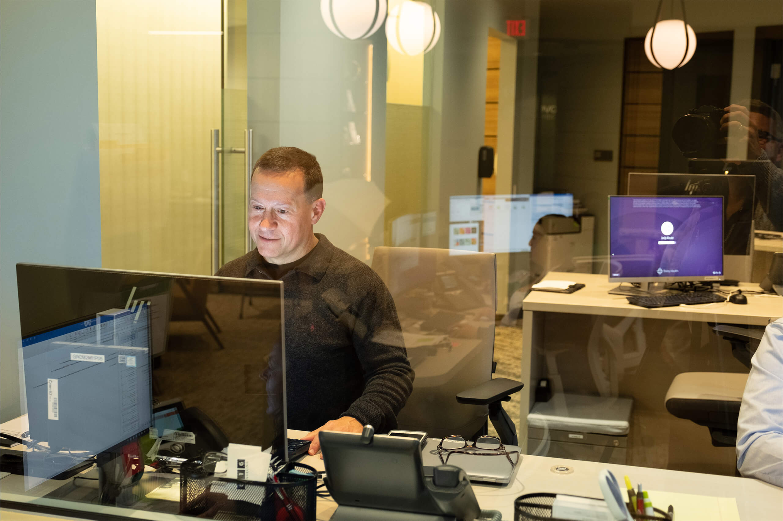 Man working in a shared work space that has multiple desks and computers.