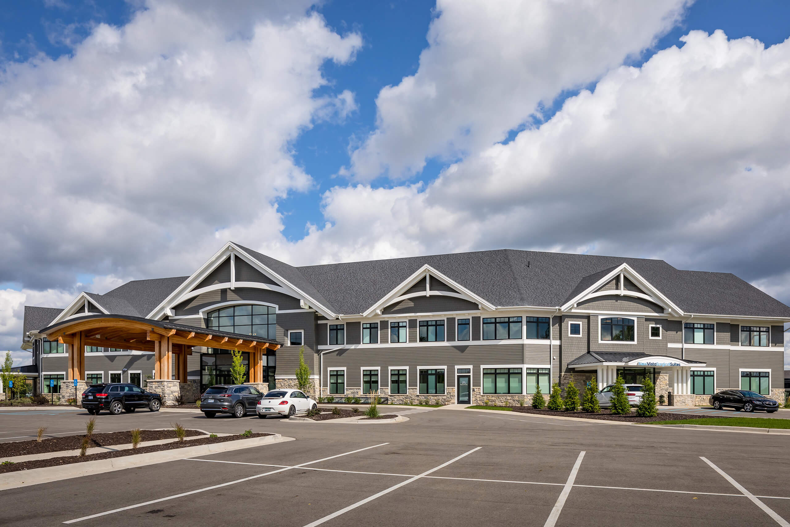 An outdoor view of a large two-story commercial building that's gray with white trim and a new parking lot