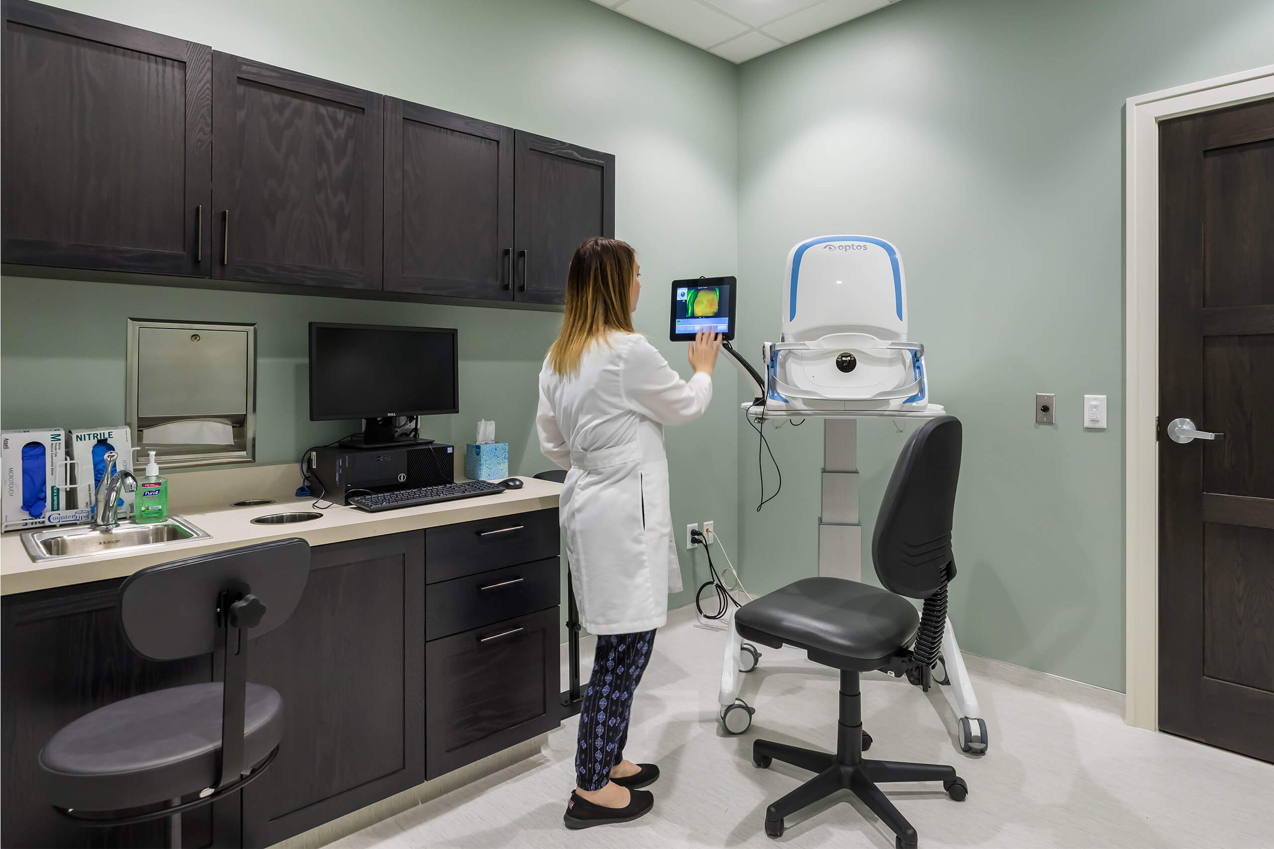 A medical professional standing and looking at a machine monitor screen