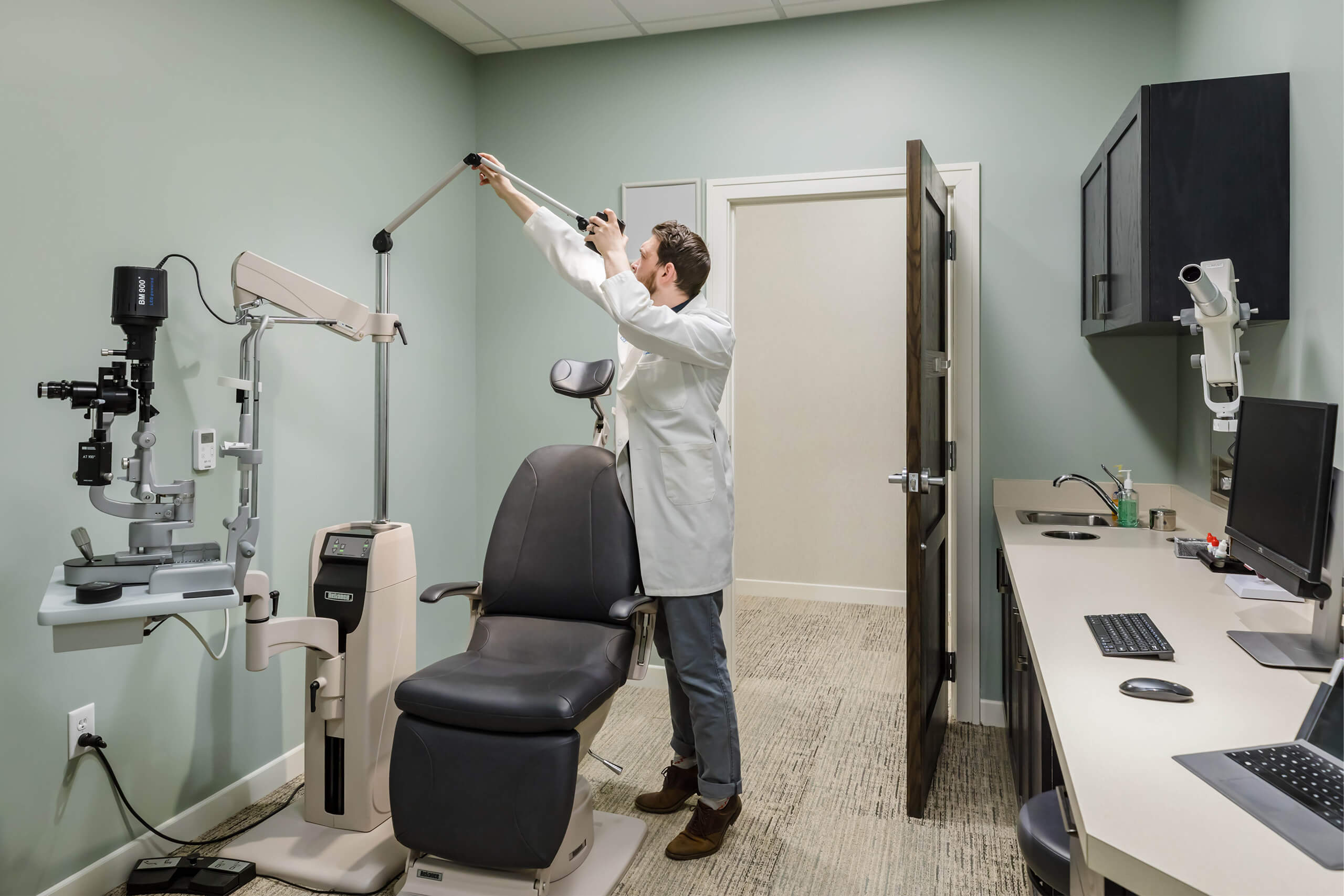 A medical professional in a white coat adjusting a machine in an examination room