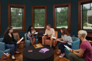 Five students seated around a round coffee table collaborating