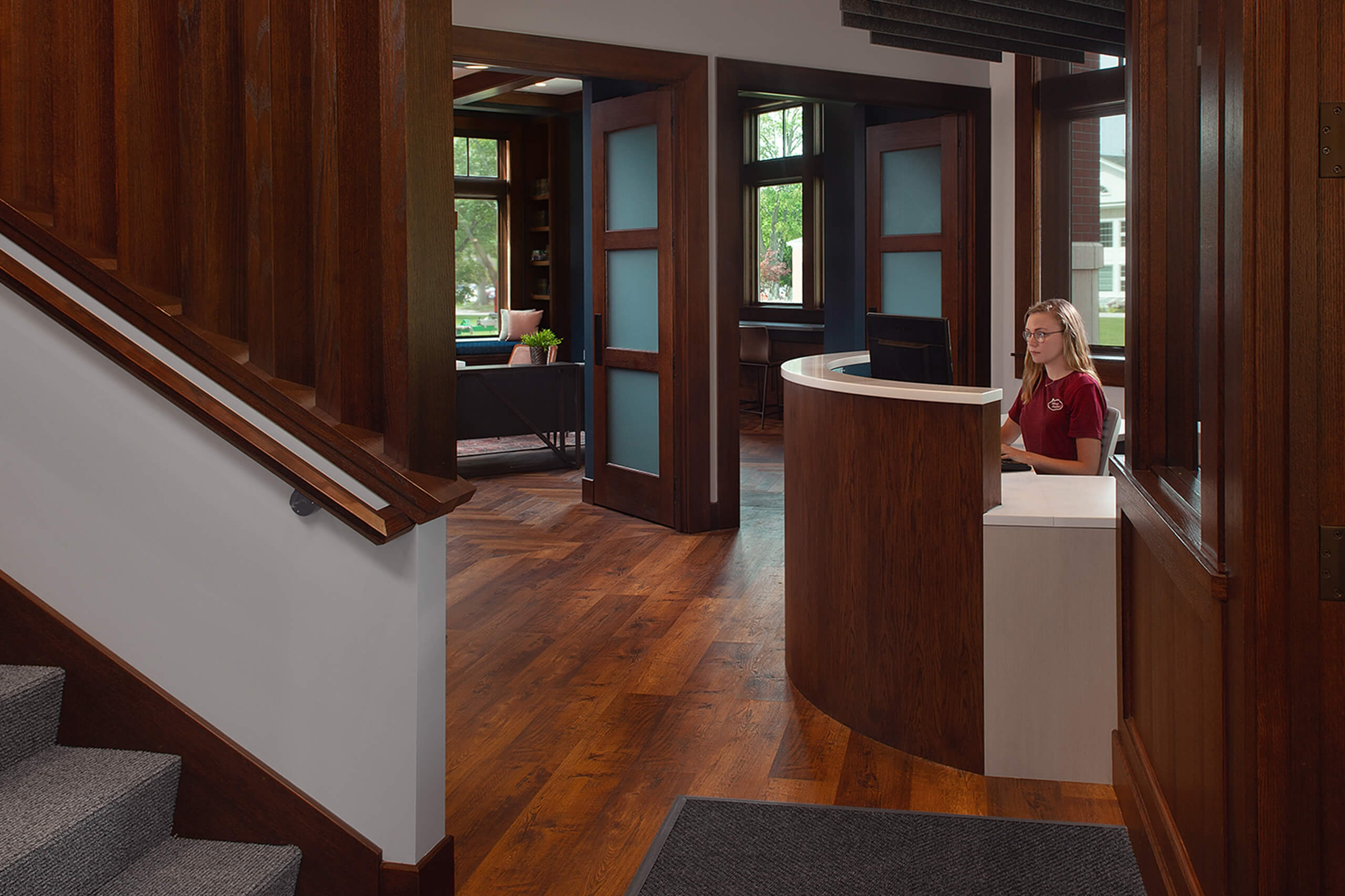 Entry way to the Hope cCollege Campus Ministries House, featuring dark wood accents on the reception desk and doors leading to a lounge area.