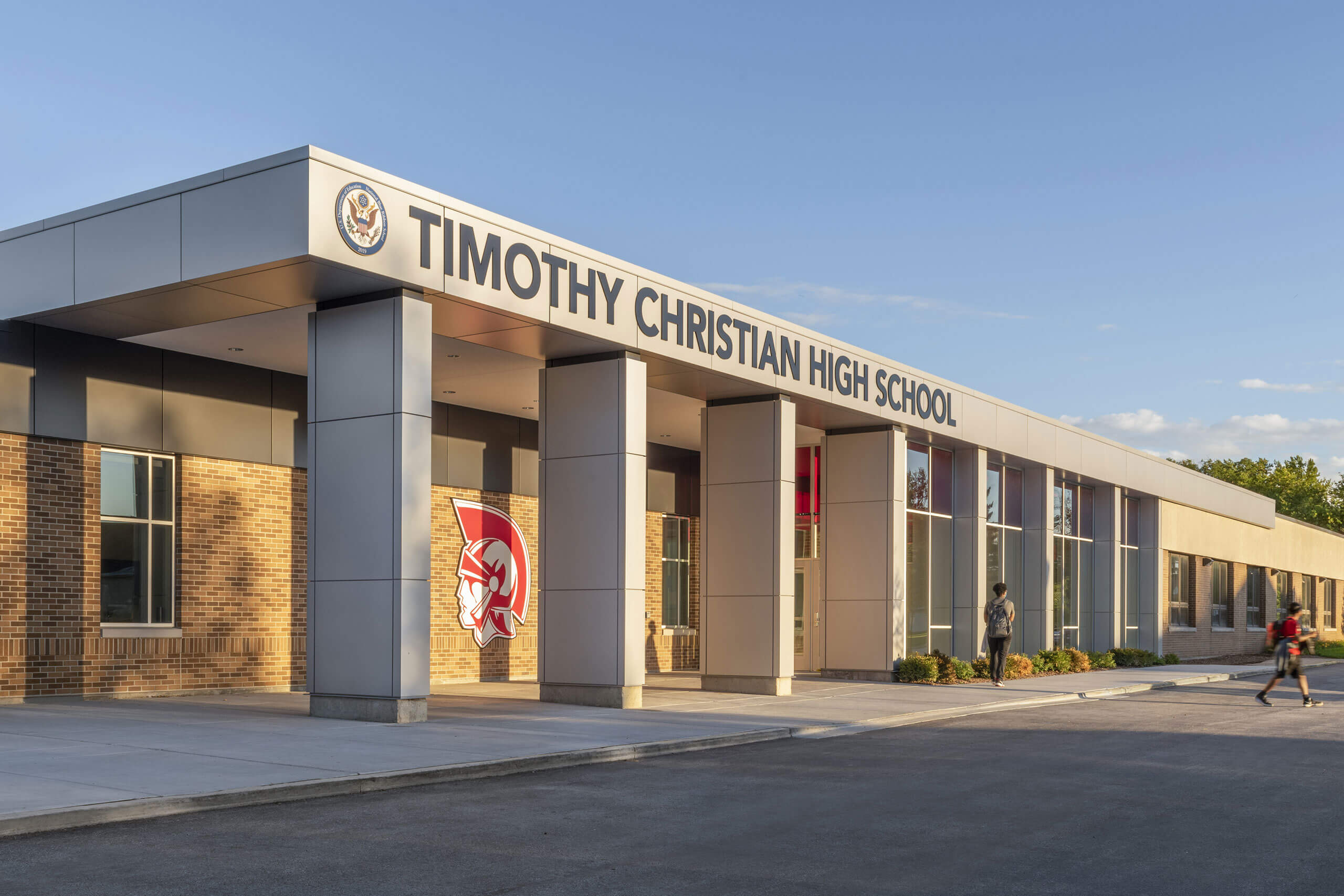 Exterior view of the Timothy Christian High School entrance featuring the logo, large windows and covered walkway