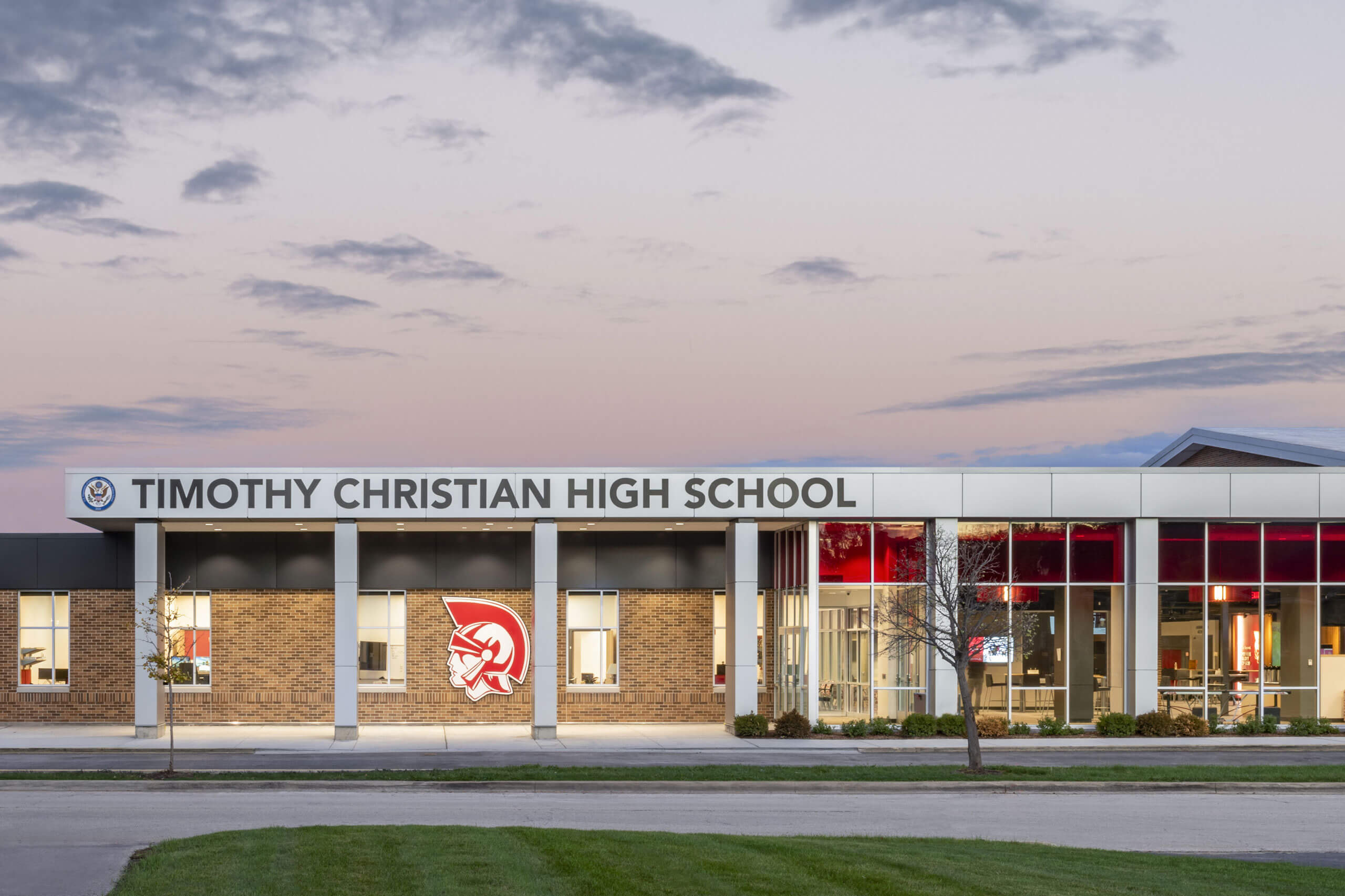 Exterior view of the Timothy Christian High School entrance featuring the logo, large windows and covered walkway