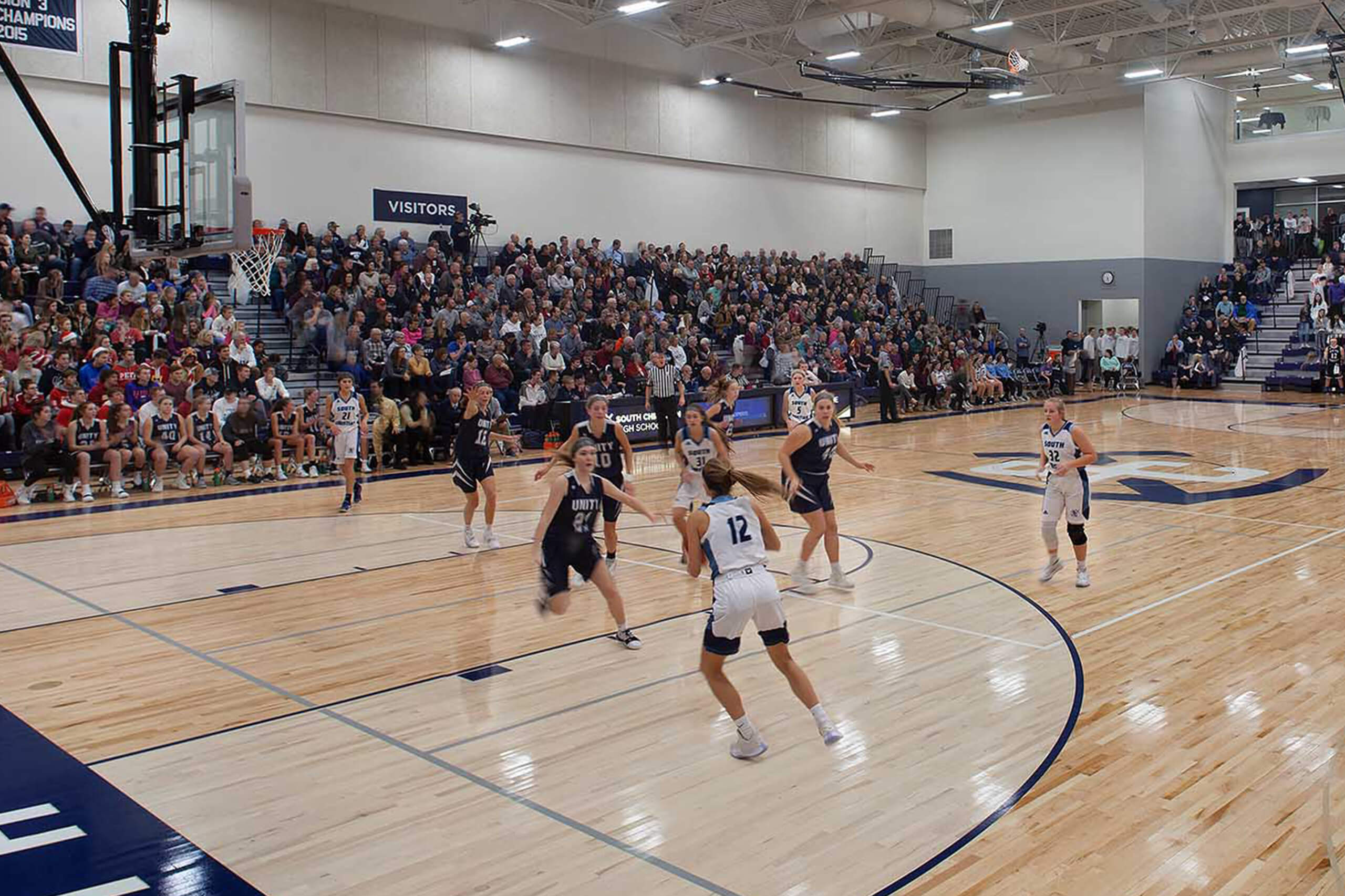 Action shot of a basketball game in a gymnasium and bleachers with spectators