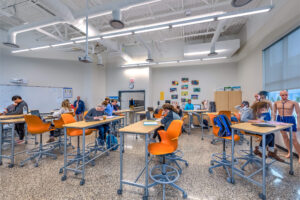 Students learning in a classroom at rectangular high-top tables