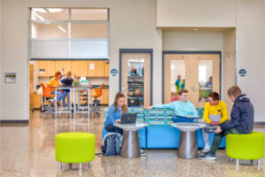 Four students sitting in an open room on blue and lime green furniture