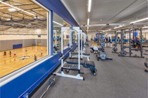 View of room with gym equipment overlooking a gymnasium with kids