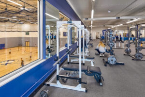 View of room with gym equipment overlooking a gymnasium with kids