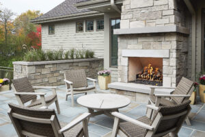 residential home exterior view of a deck with seating area and an exterior stone fireplace