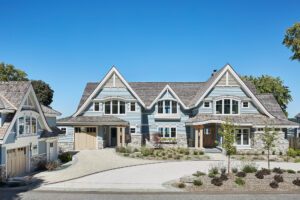 exterior photo of a residential home lakefront cottage with blue siding, white trim, exterior driveway and landscaping