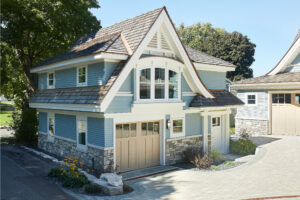 exterior photo of a residential home lakefront cottage with blue siding, white trim, exterior driveway and landscaping