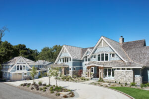 exterior photo of a residential home lakefront cottage with blue siding, white trim, exterior driveway and landscaping