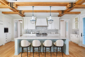 interior view of an open kitchen with barstools over an island with the stove and cabinets behind