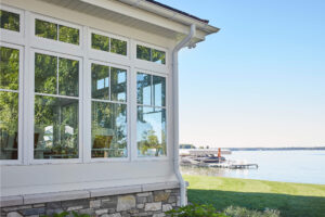 residential lakefront cottage exterior view of the sunporch windows with the yard and lake behind