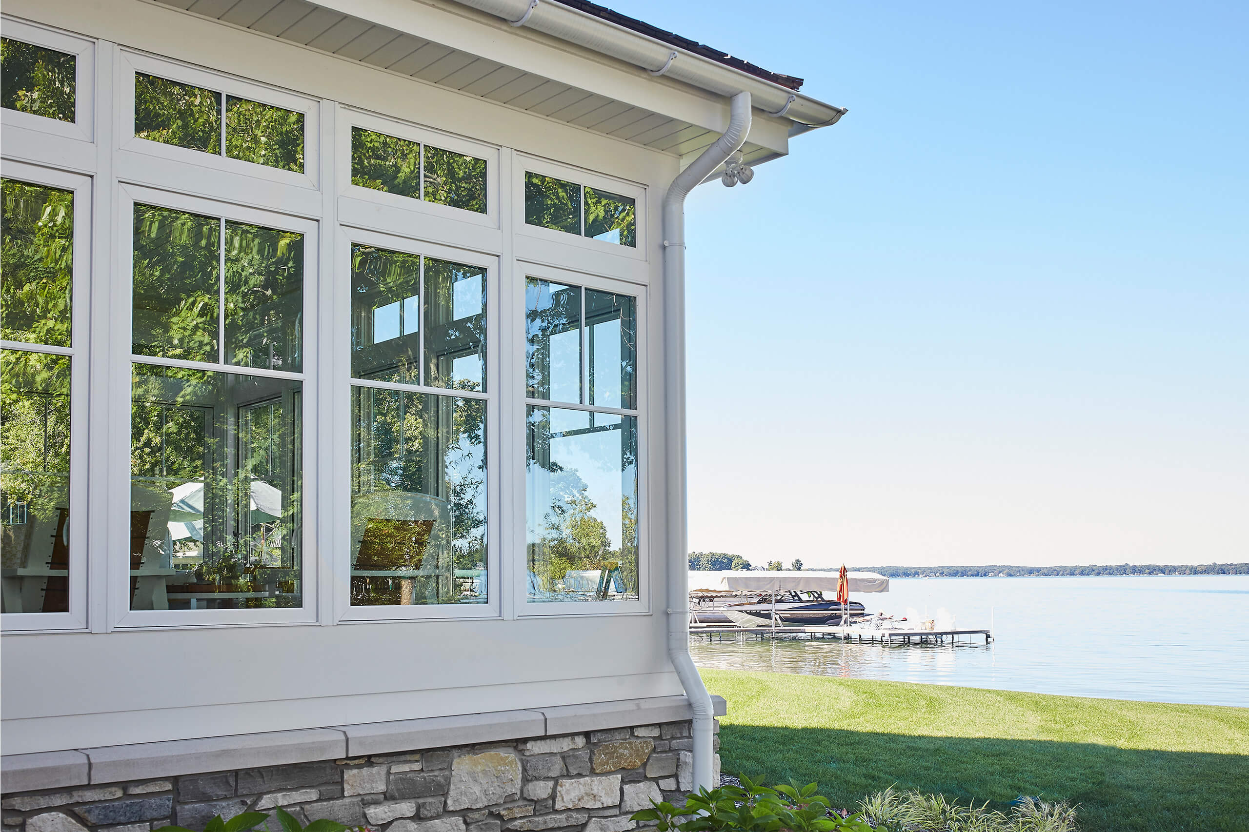 residential lakefront cottage exterior view of the sunporch windows with the yard and lake behind