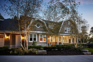 exterior view of a residential home from the driveway at dusk with porch lights lit