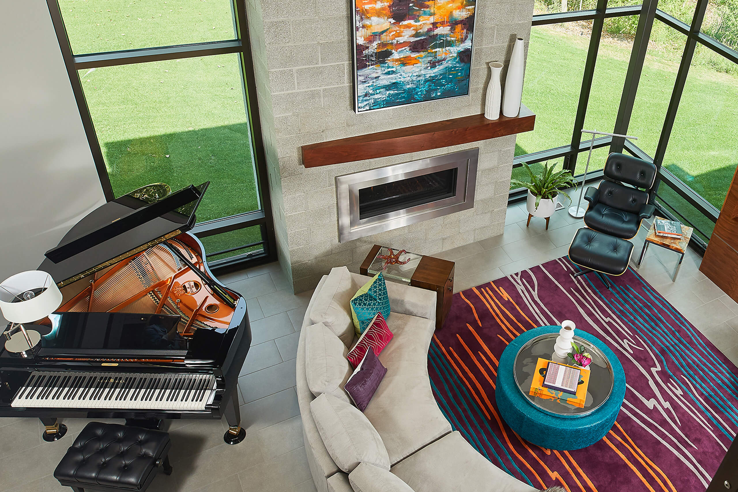 interior view of a modern home looking down into the living area with fireplace and seating and piano