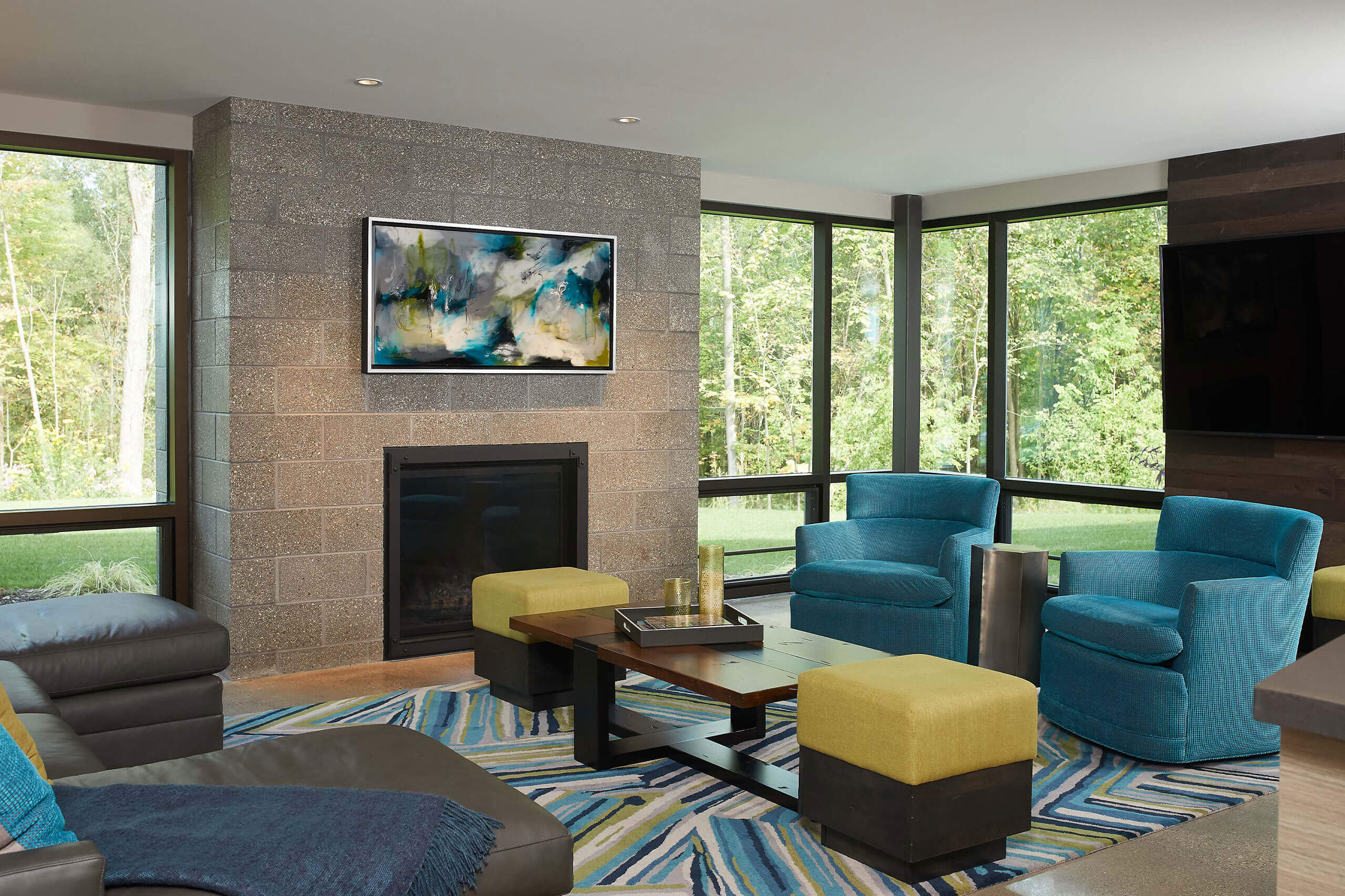 interior view of a modern home seating area in front of a fireplace decorated with teals and greens