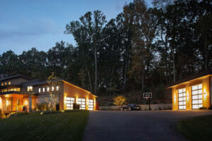 exterior view of a residential home with all lights on for the garage, entryway, and supplemental garage