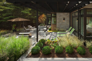 A modern patio with various levels and areas to lounge or sit with green landscaping