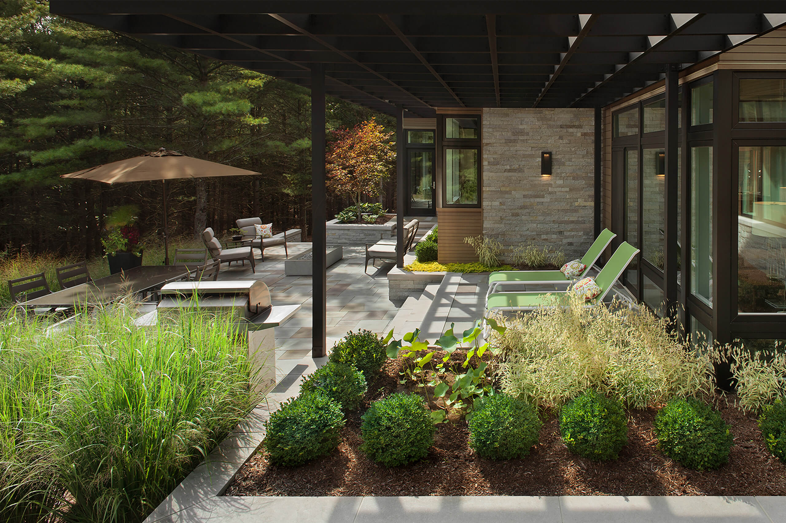 A modern patio with various levels and areas to lounge or sit with green landscaping