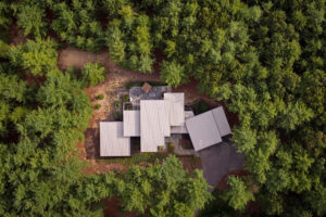 aerial view of a steel roofline of a residential home in the woods surrounded by green trees