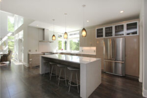 interior view of a modern residential home looking toward the kitchen island and cabinets and fridge