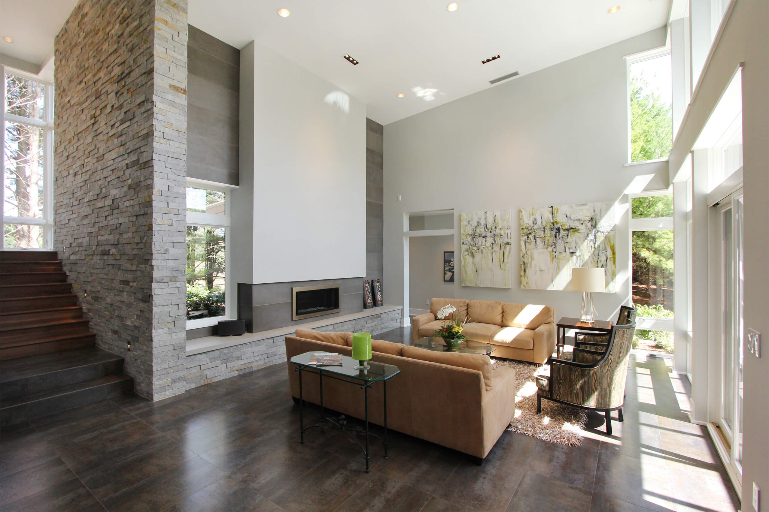 interior of a residential modern home with stairs, a stone wall around the fireplace and seating area