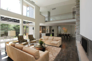 interior of a residential modern home with from the seating area facing a wall of windows and the second floor walkway