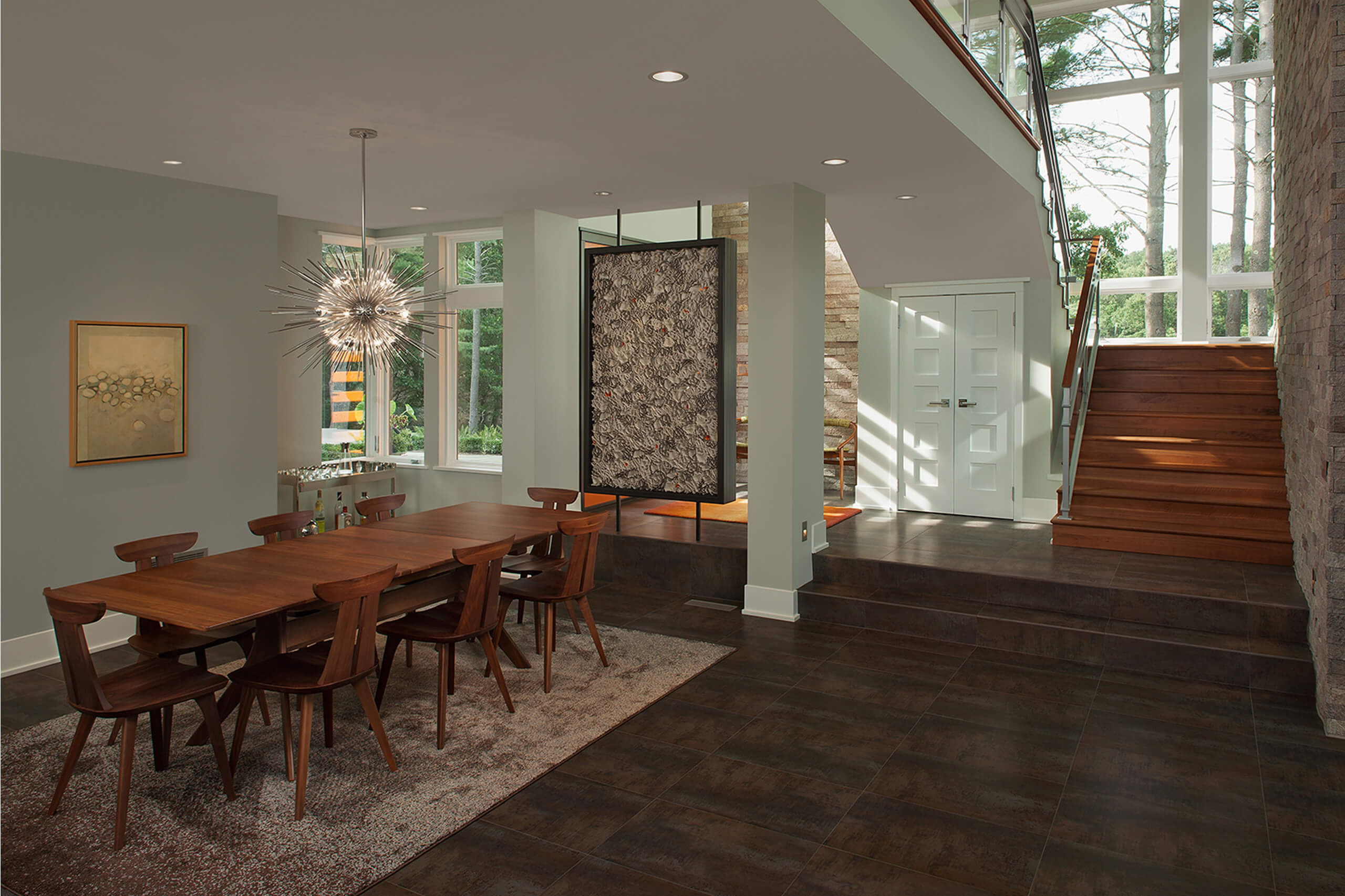 interior of a residential modern home with stairs leading down to a dining table and installed art