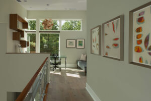 A view of an interior hallway with walls of artwork and a sitting area with a desk and bench