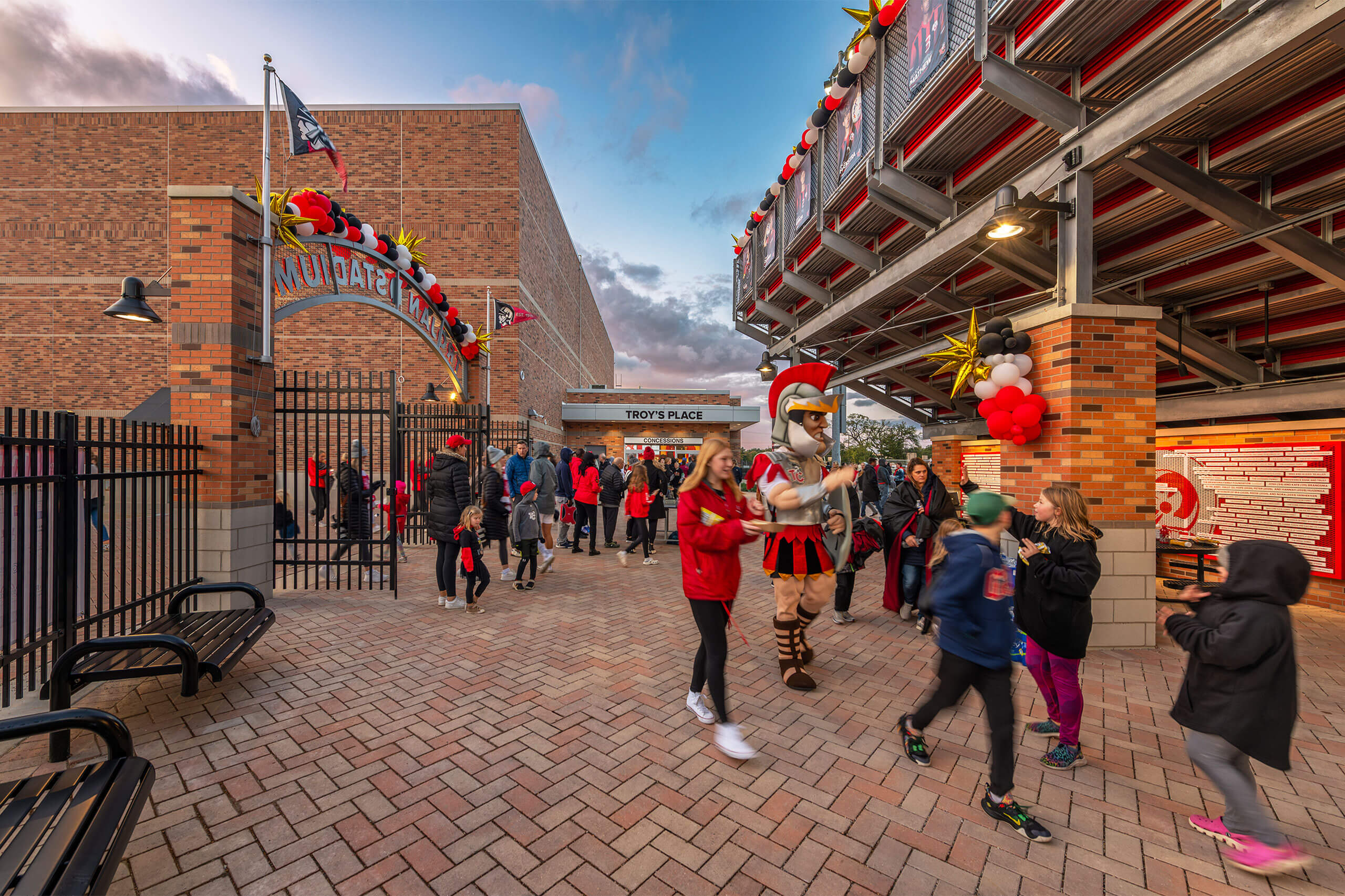 Spectators and the mascot walking through the entrance at Trojan Stadium