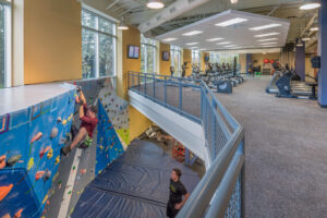 Interior view of the multi level rec center with a climbing wall on the lower level and cardio equipment on the upper level