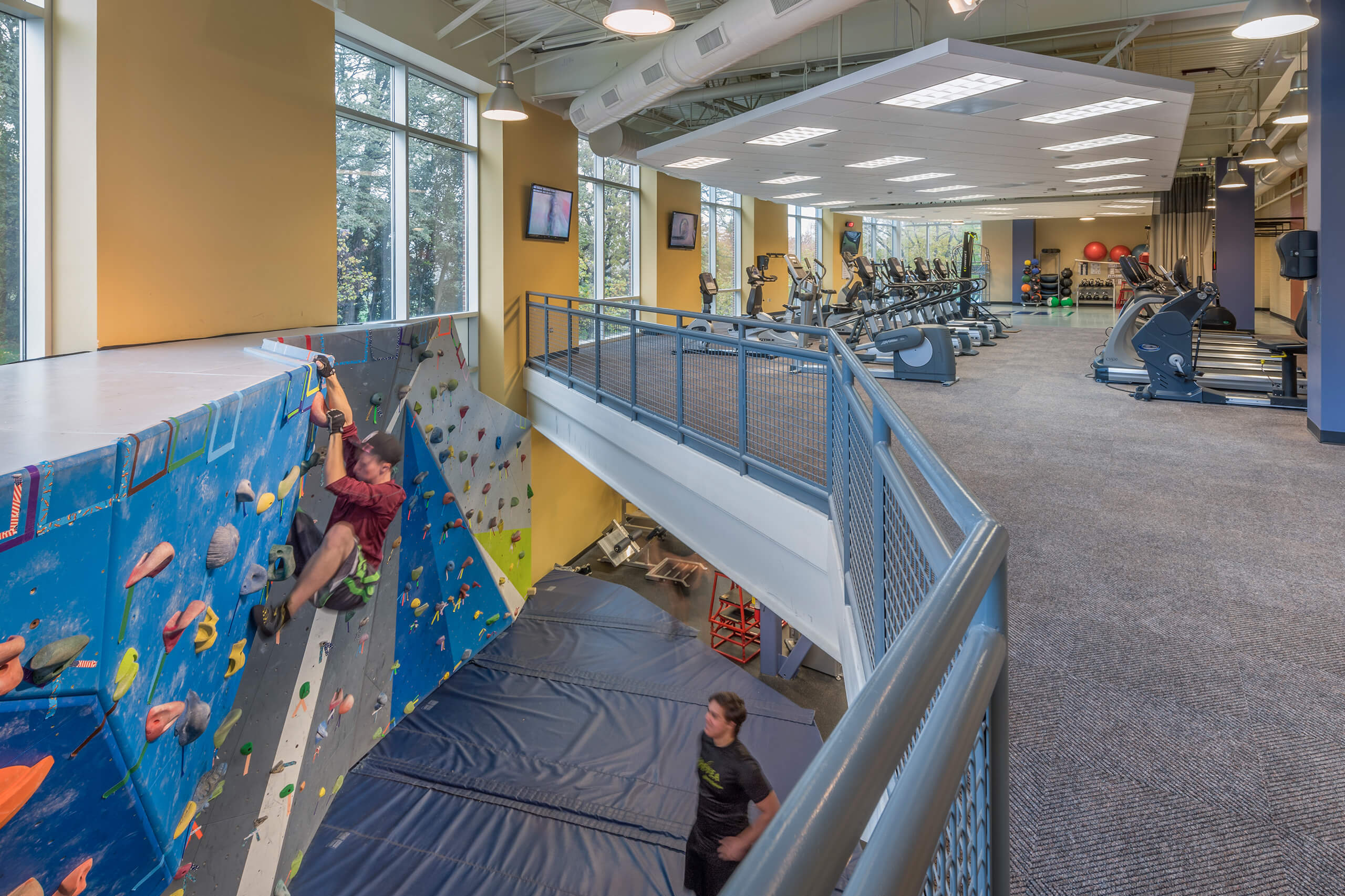 Interior view of the multi level rec center with a climbing wall on the lower level and cardio equipment on the upper level