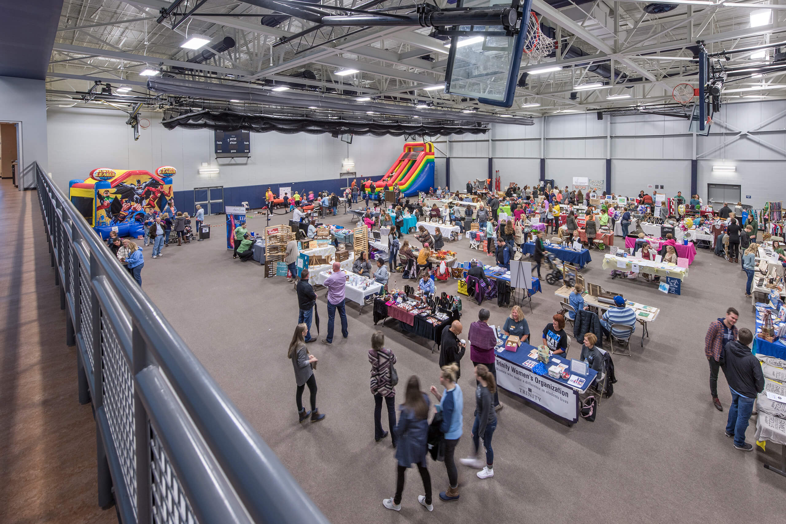 Event space with tables for different organizations as well as a bounce house in one corner and an inflatable slide in the other.