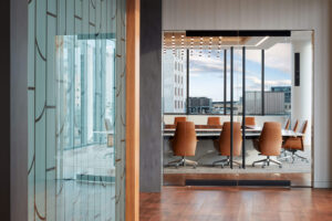 interior view of a modern city building featuring glass walled doors and a boardroom-style seating