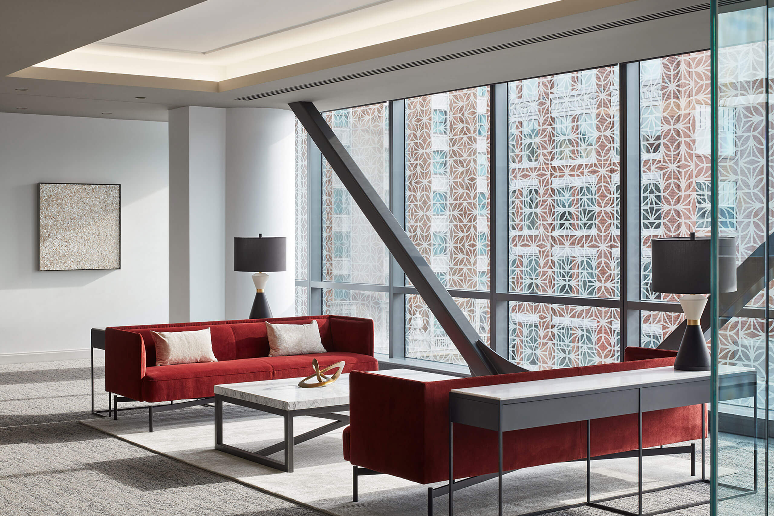 modern office workplace interior showing two red couches and glass windows facing tall buildings