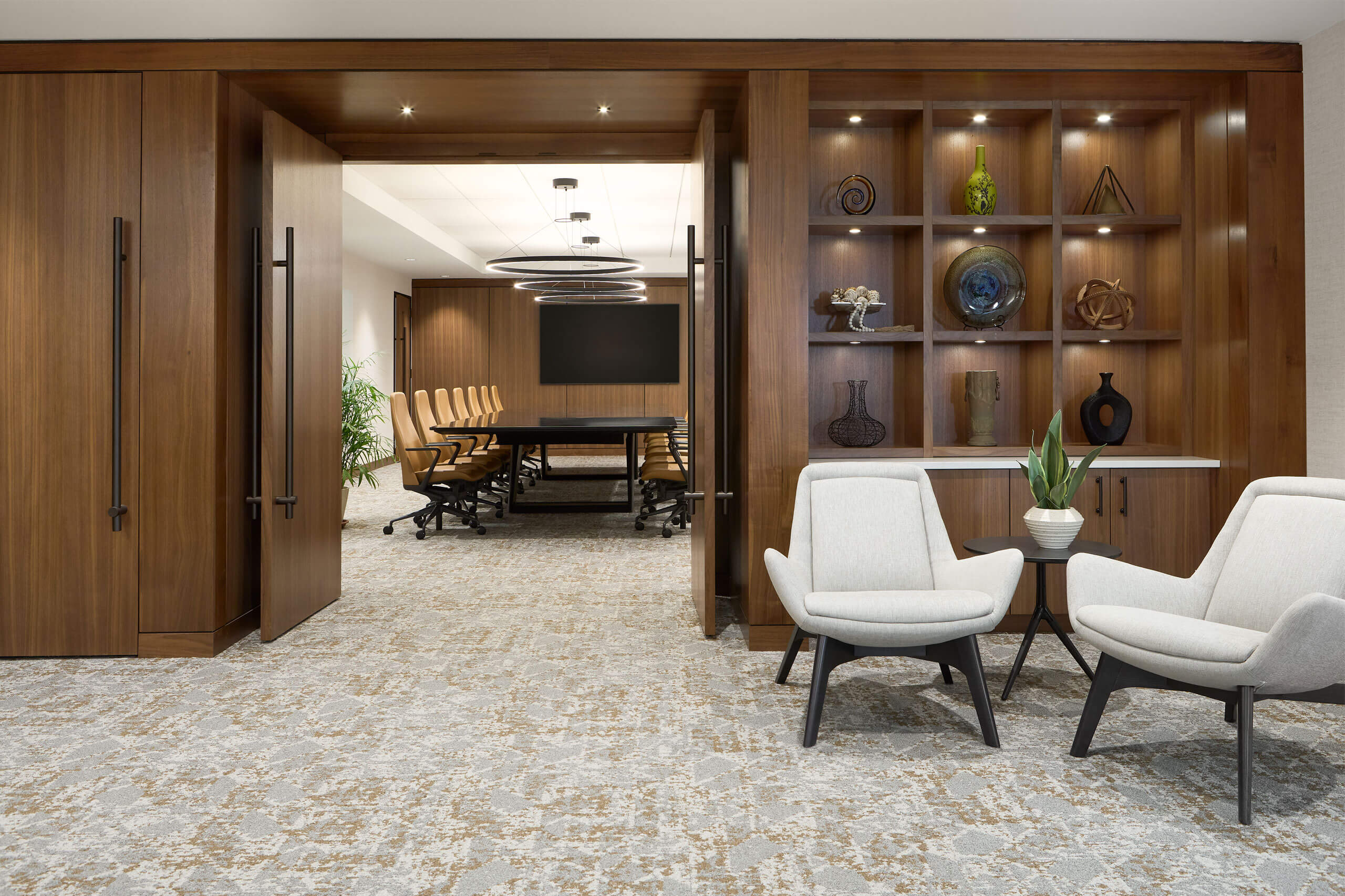 interior view of a modern office workspace with dark wood paneled doors facing a boardroom