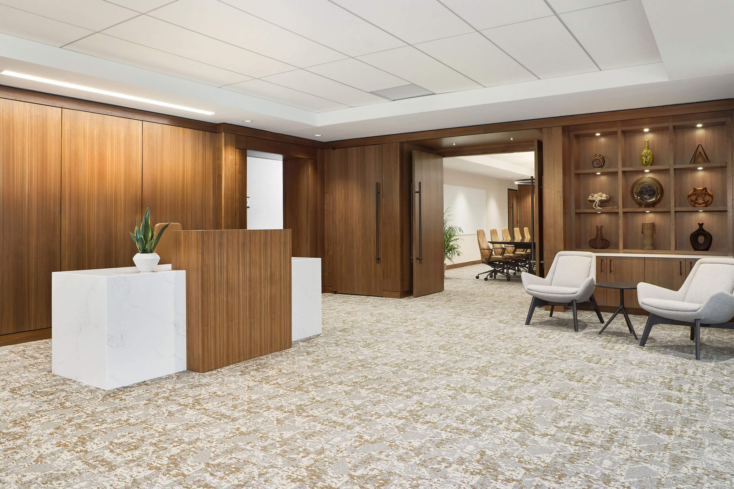 interior view of a modern office workspace with an office reception desk and dark wood paneled doors facing a boardroom