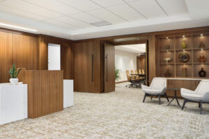 interior view of a modern office workspace with an office reception desk and dark wood paneled doors facing a boardroom