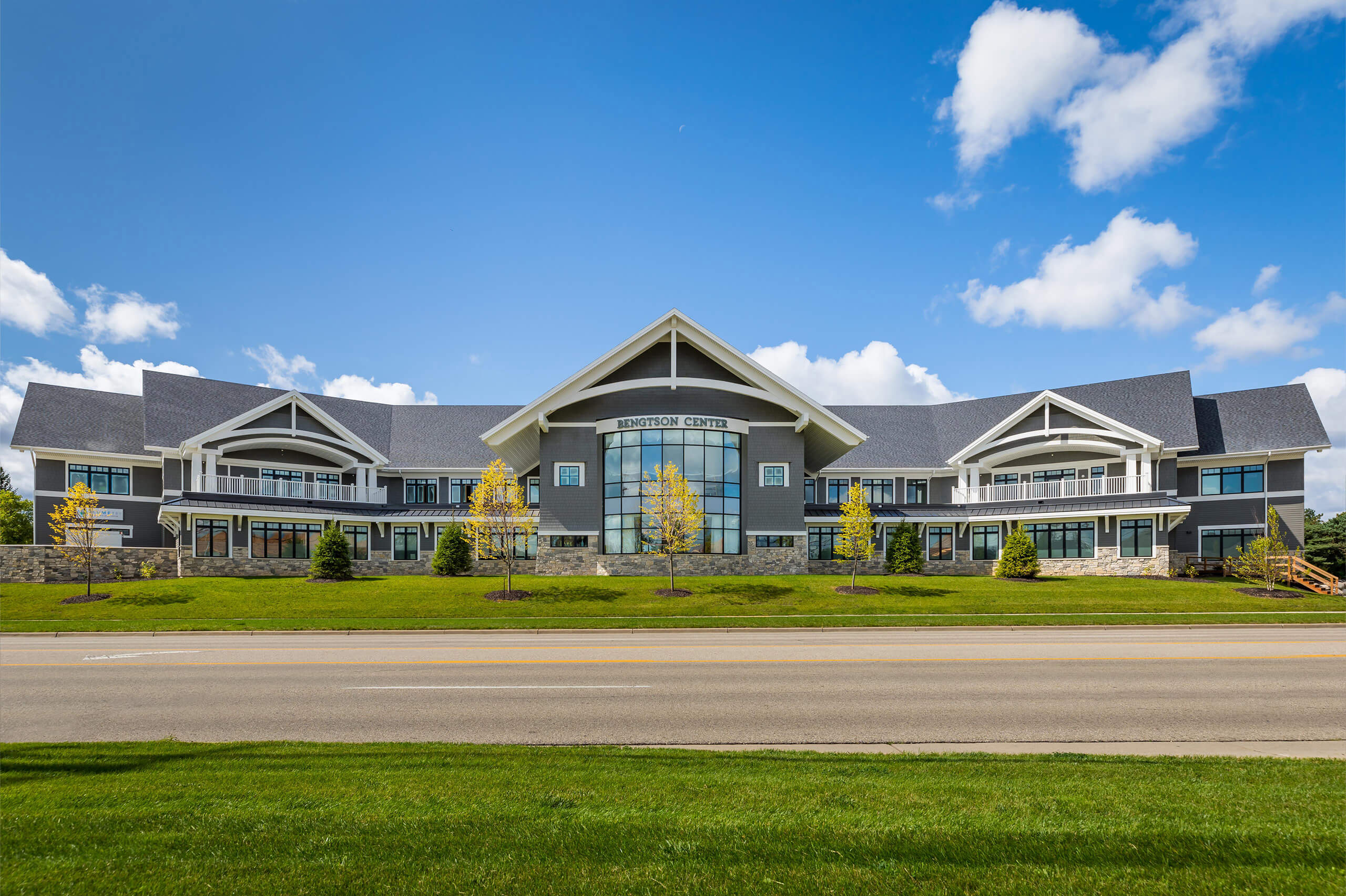 An outdoor view of a large two-story commercial building that's gray with white trim with a blue sky