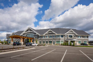 An outdoor view of a large two-story commercial building that's gray with white trim and a new parking lot