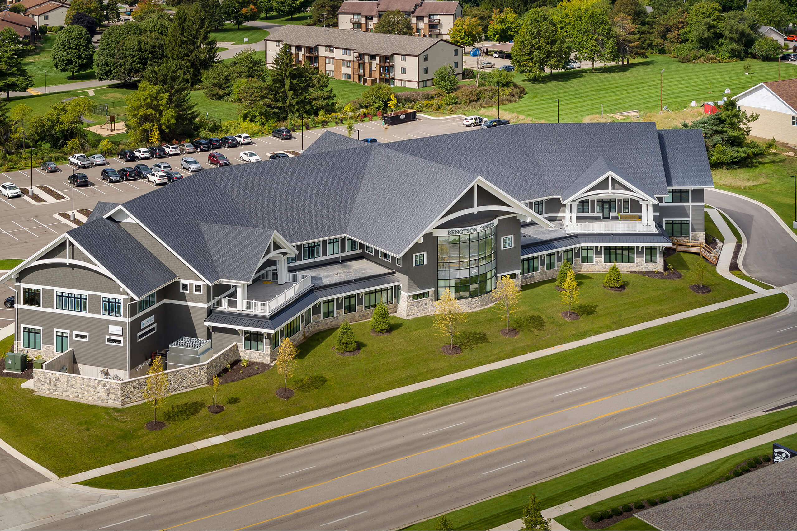 Aerial view of large gray and white building with a parking lot in the background