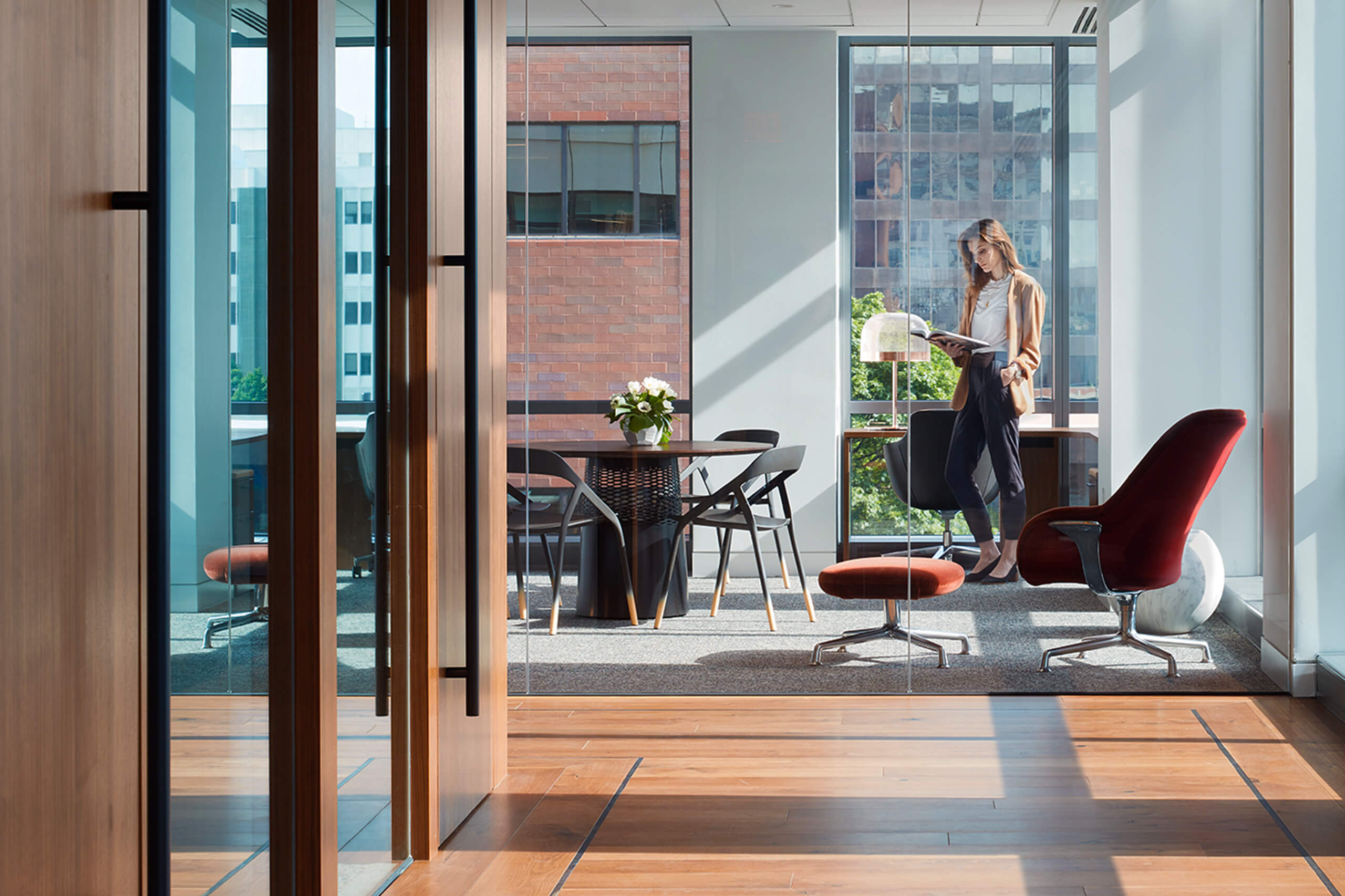 photo looking down a long hallway with wood floors to a glass-walled office at the end