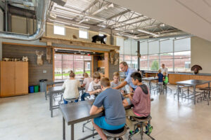 A teacher teaches four boys at a table inside the Integrated Outdoor Education building at Ada Christian School